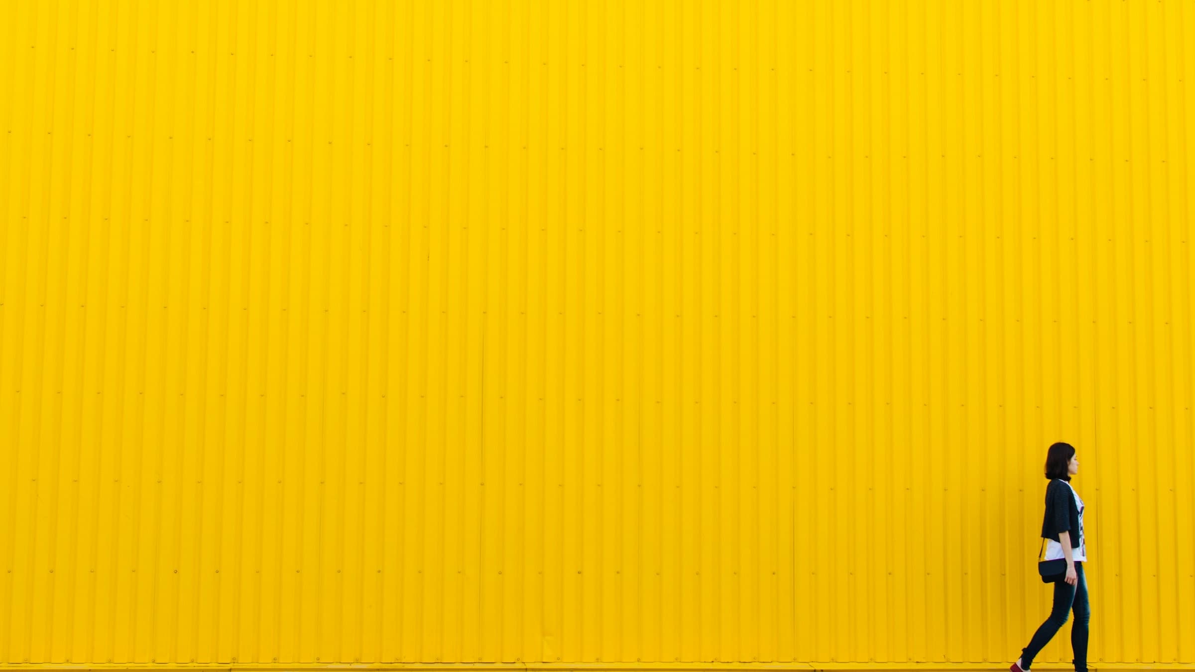Eine kleine Person vor einer riesigen gelben Wand